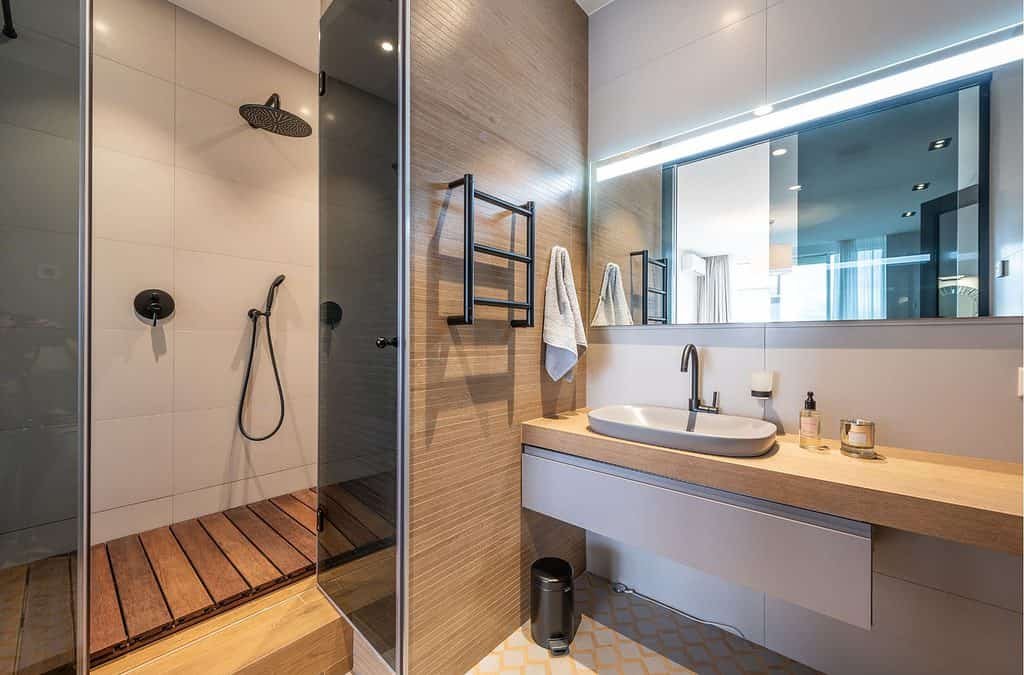 Bathroom with an oval sink and shower enclosure with wooden floor