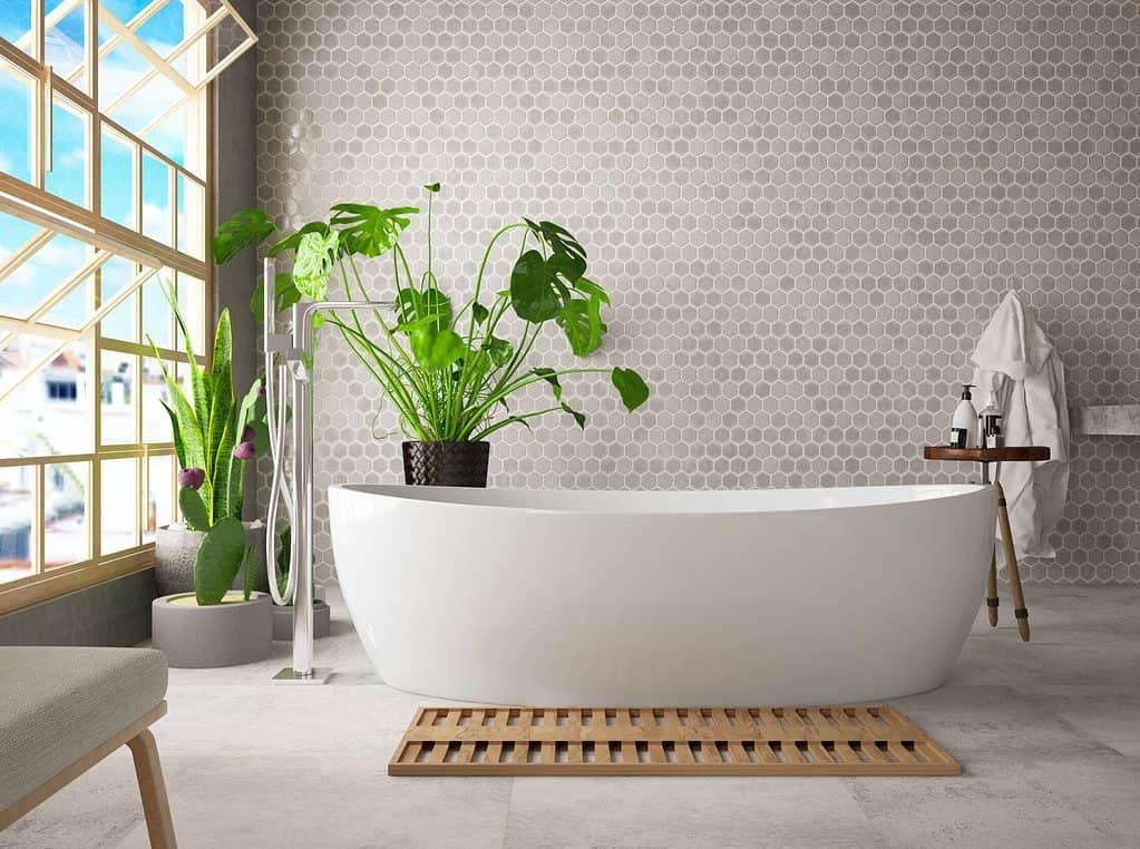Modern looking bathroom with a large white standalone bath tub in front of a wall tiled with hexagonal tiles