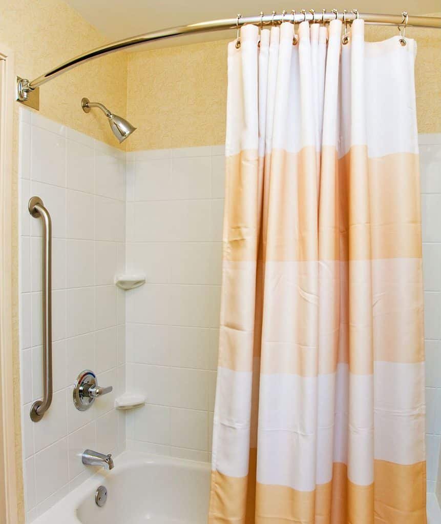 An over bath shower with an orange and white shower curtain